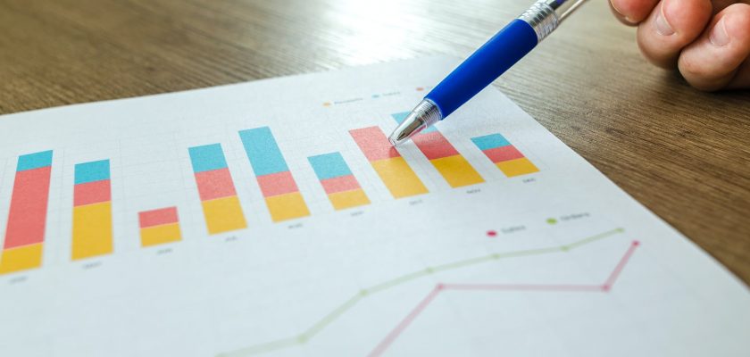 person holding pen pointing at graph