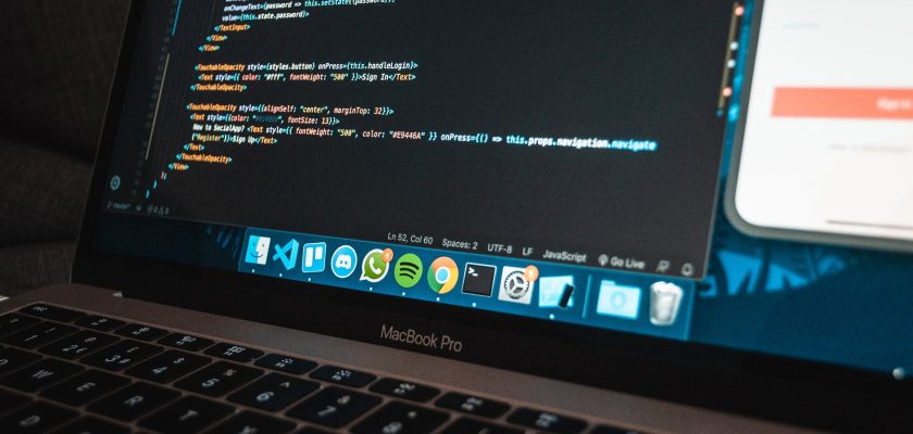 workplace with modern laptop with program code on screen