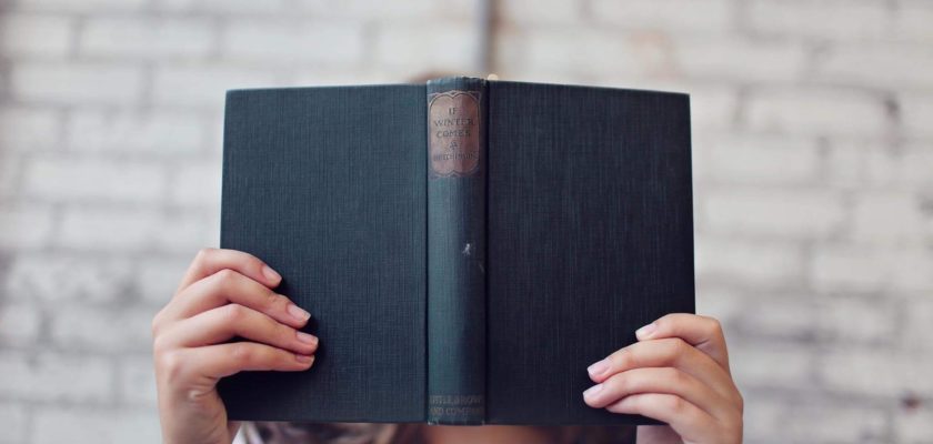 selective focus photography of woman holding book