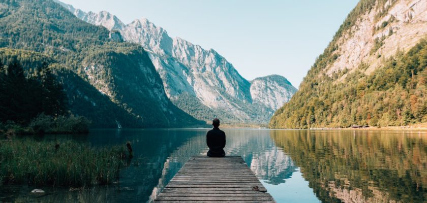 a person sitting on wooden planks across the lake scenery