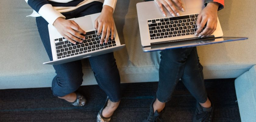 two people holding macbook pro