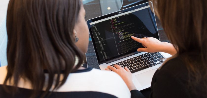 two women looking at the code at laptop